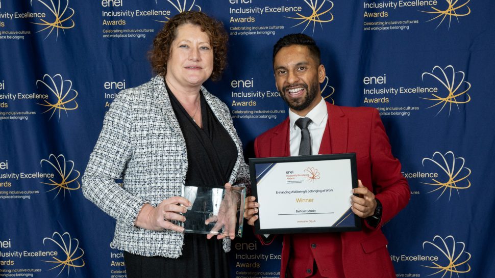 Representative from Balfour Beatty poses against the enei awards backdrop with Bobby Seagull