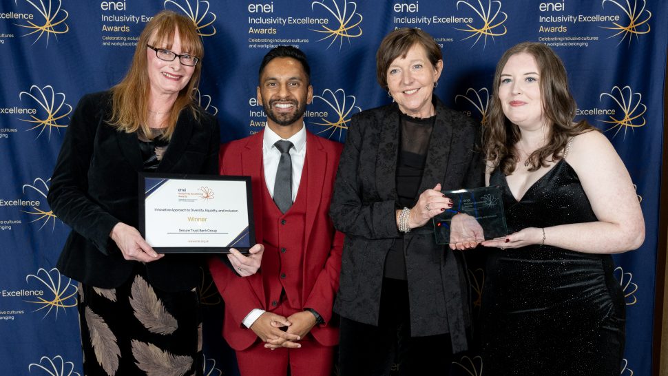 Secure Trust Bank representatives posing in front of the enei banner with Bobby Seagull.