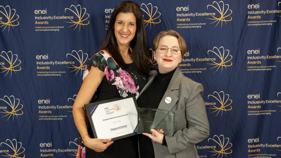 Award winners posing in front of the enei awards backdrop during the ceremony.