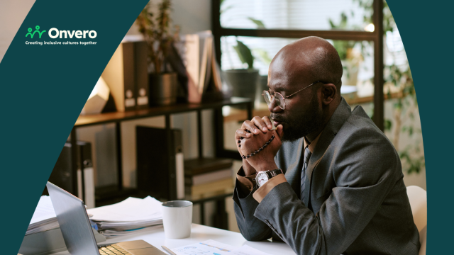 A Black man, dressed in a business suit, is sitting at an office desk in front of a laptop, with his hands holding rosary beads, seemingly deep in prayer. The Onvero branding and logo are overlaid.